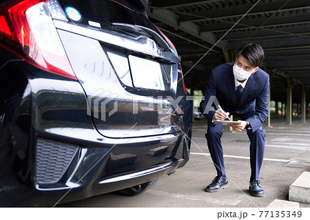 自動車をチェックするマスク姿の男性 自動車をチェックするマスク姿の男性 77135349