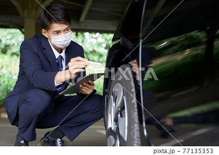 自動車をチェックするマスク姿の男性 自動車をチェックするマスク姿の男性 77135353