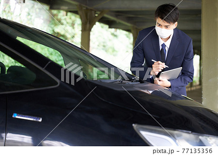 自動車をチェックするマスク姿の男性 77135356