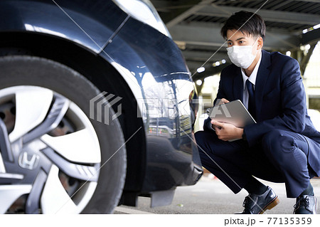 自動車をチェックするマスク姿の男性 77135359