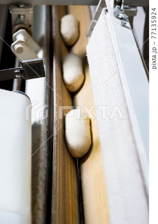 Bread dough running on conveyor belt. Food production. Bread dough running on conveyor belt. Food production. 77135924