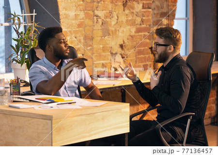 Colleagues working together in modern office using devices and gadgets during creative meeting 77136457