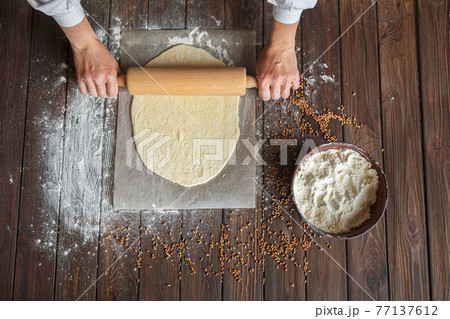 Woman's hands roll out the dough 77137612