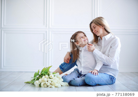 Portrait of little girl loving mother holding her and tulips 77138069