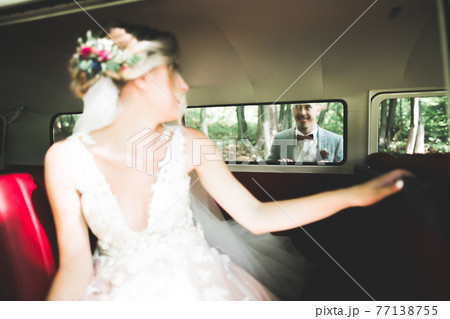 Beautiful newlywed couple posing near retro car Beautiful newlywed couple posing near retro car 77138755