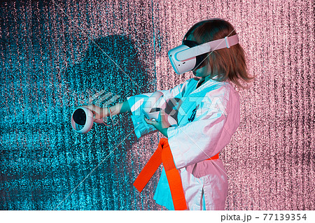 Young caucasian girl in karate uniform playing video games with virtual reality 77139354