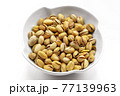 A white bowl with a bunch of salted and roasted pistachio seeds on a white background. Perfect shot for vegan diet,. 77139963