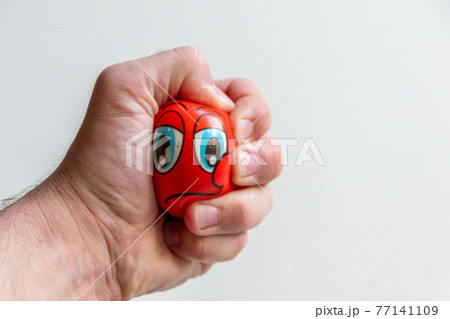 Male hand squeezing a ball with an angry face...の写真素材