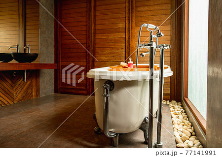 Vintage bathtub and large window with sinks in wooden bathroom. Vintage bathtub and large window with sinks in wooden bathroom. 77141991