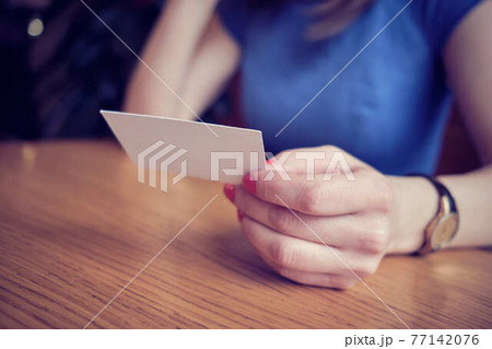 The girl in the cafe holds a business card. Concept of new design for your business. The girl in the cafe holds a business card. Concept of new design for your business. 77142076