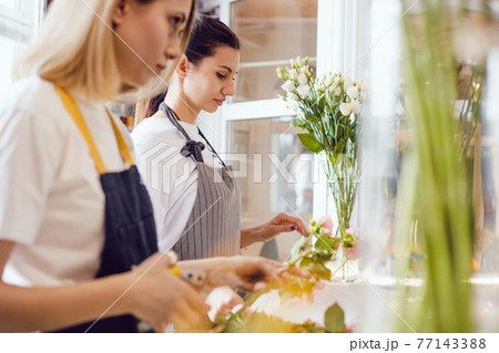 Two women florist at work in a flower shop. 77143388