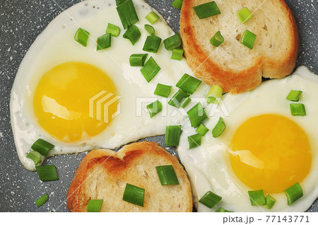 breakfast with fried eggs and green onions and baguette 77143771