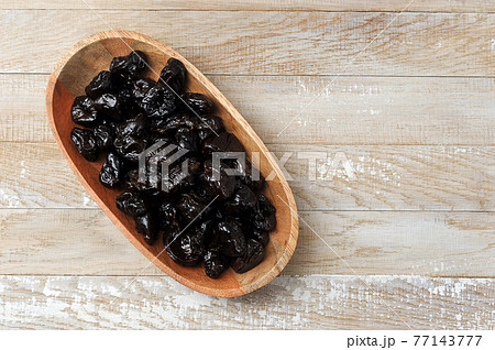 prunes in a wooden plate on a wooden background prunes in a wooden plate on a wooden background 77143777