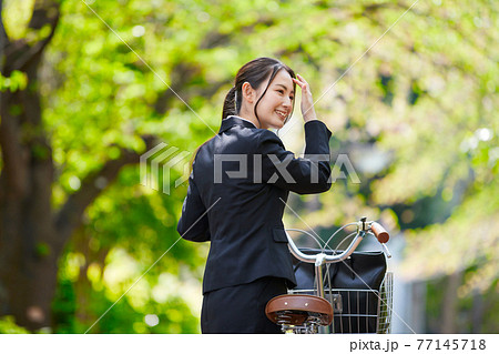 自転車を引くリクルートスーツの若い女性の写真素材