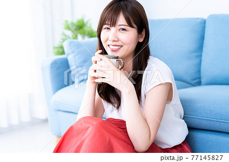 リビングでコーヒーを飲みながらくつろぐ女性 リビングでコーヒーを飲みながらくつろぐ女性 77145827