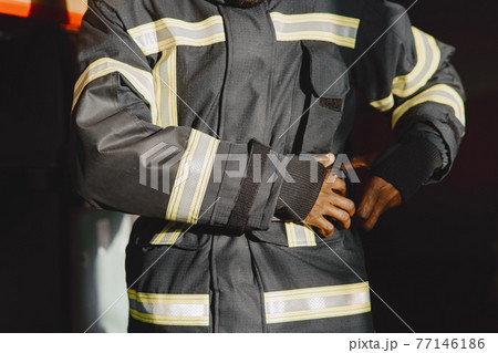 Portrait of a firefighter standing in front of a fire engine 77146186
