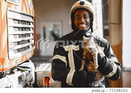 Portrait of a firefighter standing in front of a fire engine 77146203