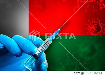 Madagascar Covid-19 Vaccination Campaign. Hand in a blue rubber glove holds a syringe with covid-19 virus vaccine in front of Madagascar flag Madagascar Covid-19 Vaccination Campaign. Hand in a blue rubber glove holds a syringe with covid-19 virus vaccine in front of Madagascar flag 77146511