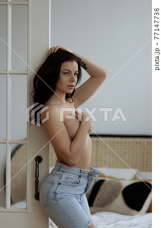 Sensual woman with bare breast standing near window Sensual woman with bare breast standing near window 77147736