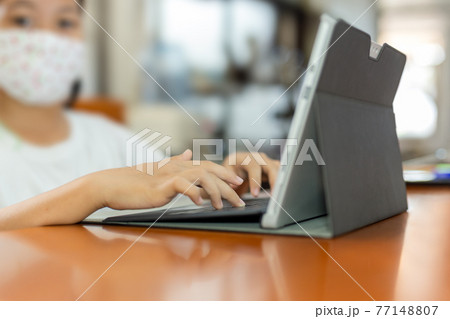 Young child student with protective mask hands typing on laptop. 77148807