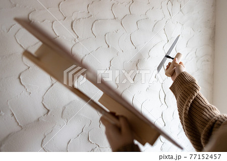 工事中の新築一戸建ての壁に珪藻土を塗っている若い女性 工事中の新築一戸建ての壁に珪藻土を塗っている若い女性 77152457