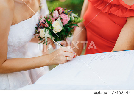 The bride signs the wedding certificate during the wedding ceremony, close-up. The bride signs the wedding certificate during the wedding ceremony, close-up. 77152545