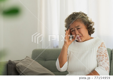 Asian Elderly man with a headache sitting on a bed in morning 77154959