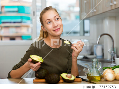 Happy housewife cooking with avocado at home kitchen 77160753