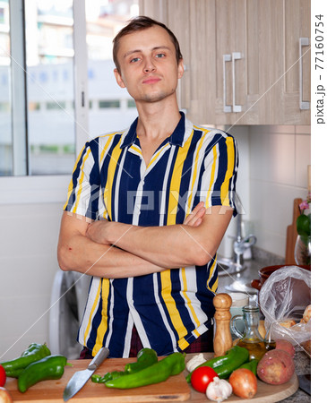 Proud man with arms crossed stands at the kitchen table Proud man with arms crossed stands at the kitchen table 77160754