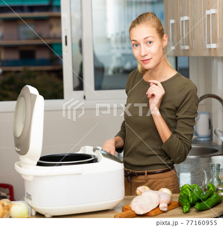 Housewife cooks soup in slow cooker in the kitchen 77160955