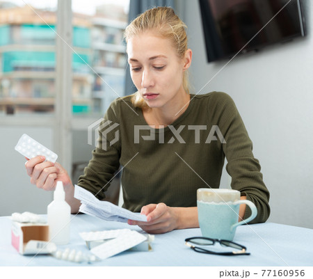 Frustrated girl taking her numerous pills at home 77160956