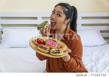 Unhealthy eating concept. Overweight fat woman holding plate with doughnut and eating Unhealthy eating concept. Overweight fat woman holding plate with doughnut and eating 77161550
