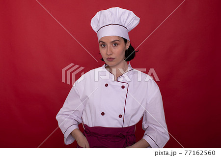 Portrait of beautiful female chef standing on isolated red background 77162560