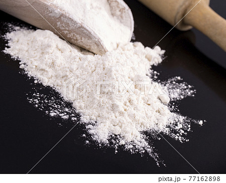 The white flour with a rolling pin on black 77162898