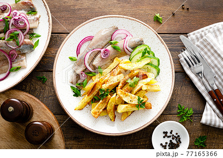 Pickled herring fillet with onion and fried potato on plate 77165366