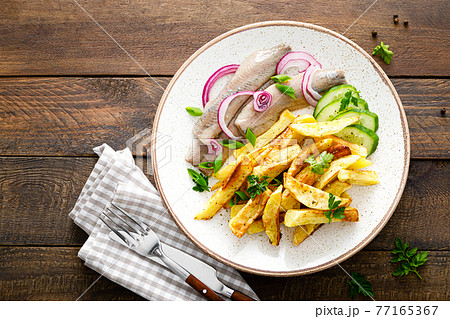 Pickled herring fillet with onion and fried potato on plate Pickled herring fillet with onion and fried potato on plate 77165367
