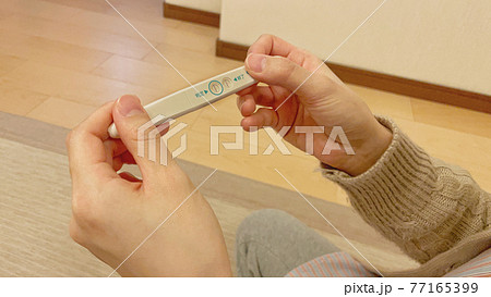 妊娠検査薬の陽性反応を確認しているところの写真素材