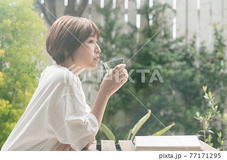 テラスで読書する若い女性 77171295