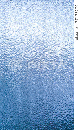 Raindrops on the glass in rainy weather.The glittering, shiny surface of water on glass.Water drops in the form of balls or spheres.Blue raindrops background. Abstract backgrounds ornament with water 77173270
