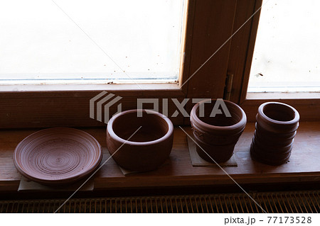 Handmade earthenware on a shelf in a store. Pot, bowl, plate, clay mug. 77173528