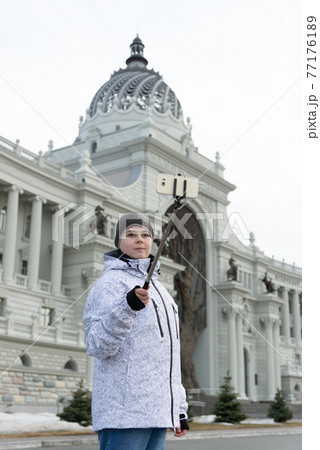 boy does selfie on phone with self-stick against backdrop landmark building boy does selfie on phone with self-stick against backdrop landmark building 77176189