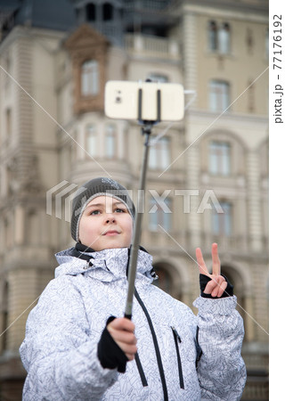 boy does selfie on phone with self-stick against backdrop landmark building boy does selfie on phone with self-stick against backdrop landmark building 77176192