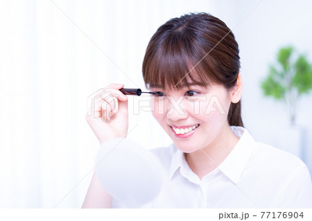 手鏡を見ながらマスカラを塗る女性 手鏡を見ながらマスカラを塗る女性 77176904