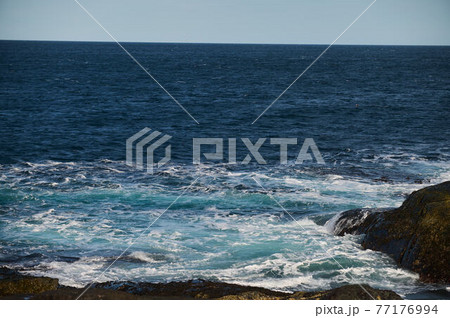 Small sea waves break against the stones of the shore. A bright sunny day and white foam of the waves. Melting glaciers as an environmental impact of air pollution. Small sea waves break against the stones of the shore. A bright sunny day and white foam of the waves. Melting glaciers as an environmental impact of air pollution. 77176994