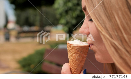 The girl eats an ice cream cone on the street of the city. The girl eats an ice cream cone on the street of the city. 77177143