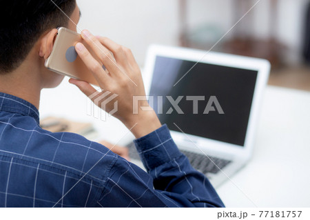 Young asian man talking phone and work from home with laptop computer. 77181757