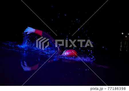 real triathlon athlete swimming in dark night 77186398