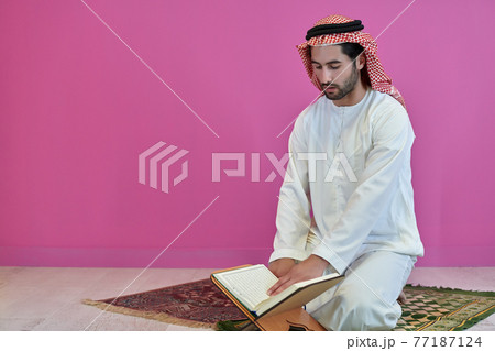 Young muslim man reading Quran during Ramadan 77187124