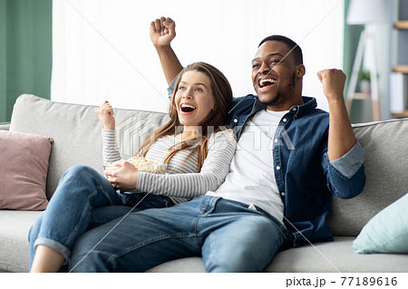 Home Entertainment. Happy Interracial Couple Watching Tv And Cheering Sports At Home Home Entertainment. Happy Interracial Couple Watching Tv And Cheering Sports At Home 77189616