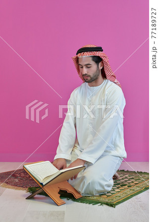 Young muslim man reading Quran during Ramadan Young muslim man reading Quran during Ramadan 77189727